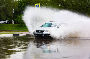 - Rusya. Moskova. 30 Mayıs 2020. Bir araba su birikintisinin içinden su sıçratarak geçiyor. Şehirde bahar seli.