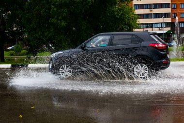 - Rusya. Moskova. 30 Mayıs 2020. Bir araba su birikintisinin içinden su sıçratarak geçiyor. Şehirde bahar seli.