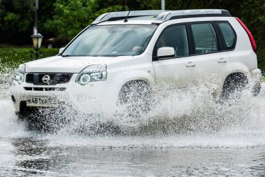 - Rusya. Moskova. 30 Mayıs 2020. Bir araba su birikintisinin içinden su sıçratarak geçiyor. Şehirde bahar seli.
