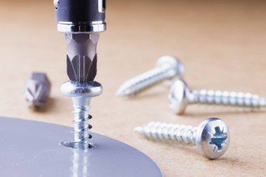 Vida metal parça tornavida ile ahşap yüzeye.