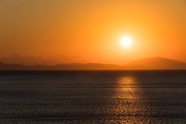 Deniz ve dağlar ufukta üzerinde gündoğumu.