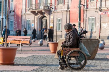Timisoara, Romanya - 29 Kasım 2016: Adam sokakta yürürken tekerlekli sandalyede. Arka görüş. Gerçek insanlar.