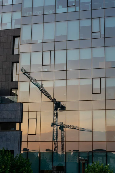 Cranes reflecting in the windows of a big building. Glass reflection.