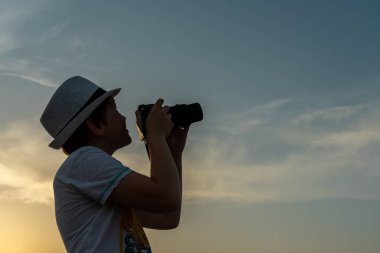 Kameralı çocuk gökyüzünde uçak arıyor.