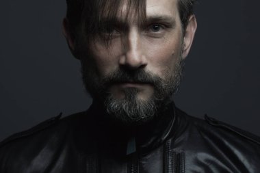 Her yaşta çok iyi. 40 yaşındaki adam koyu gri arka plan üzerinde siyah deri ceket ayakta portresi. Uzun saç alın. Rocker, motorcu tarzı. Yakın çekim. Stüdyo vurdu