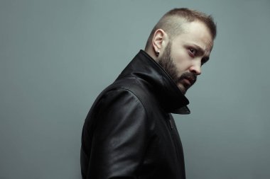 Rock yıldız kavramı. Işık gri arka plan üzerinde ayakta 35 yaşındaki adam portresi. Modern saç kesimi. Rocker, motorcu tarzı. Yakın çekim. Boşluk. Stüdyo vurdu