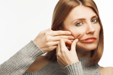 Anti-yaş yordamlar, sanat Beauty kavramı. 35 yaşında gülümseyen güzel kadın parlak uzun saçlı beyaz arka plan üzerinde izole yanak derisi çekerek komik portresi. Yakın çekim. Stüdyo vurdu