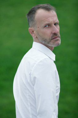 Her yaşta çok iyi. Yeşil çim arka planda beyaz gömlek üzerinde ayakta 45 yaşındaki adam portresi. Yakın çekim. Klasik tarzı. Gri saç. Açık atış