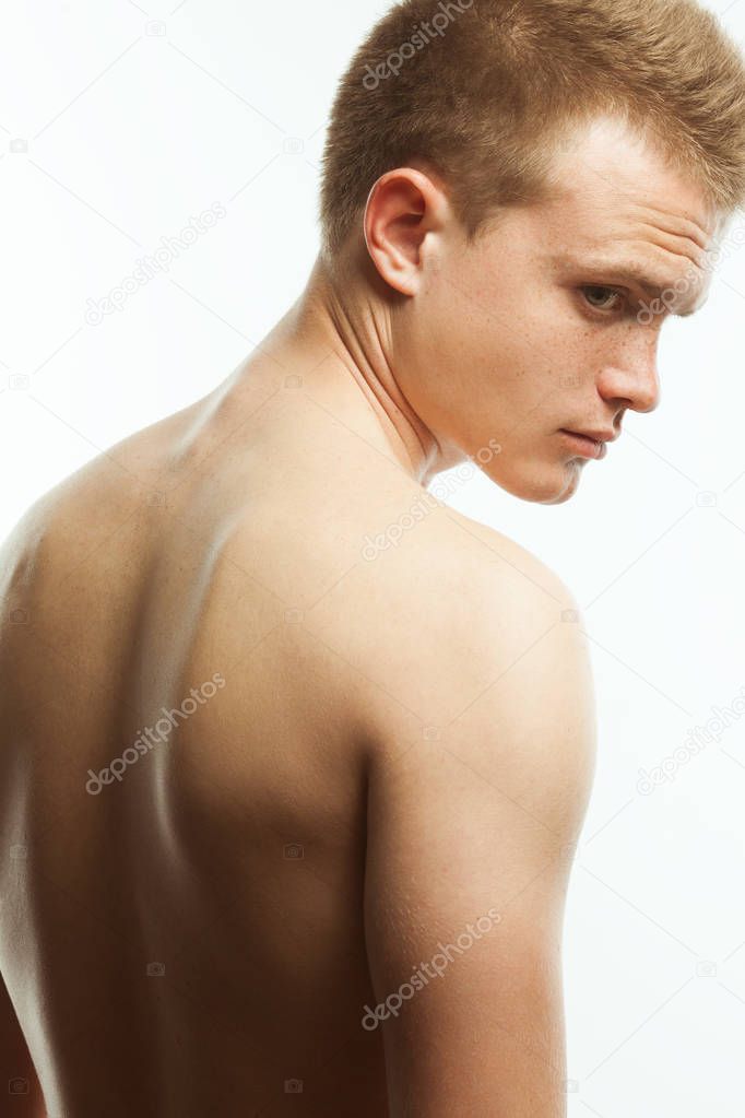 Natural male beauty concept. Close up portrait of handsome charismatic young man's back posing over white background. Studio shot