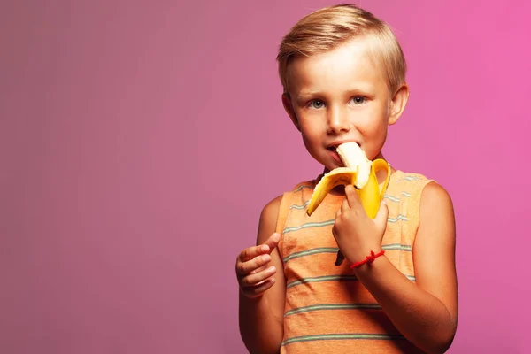 Веганский мальчик, сладкоежка концепция. Забавный портрет улыбающегося мальчика с бананом — стоковое фото