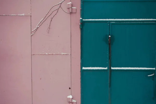 Murallas de la ciudad en concepto de invierno. Puertas de metal rosa y azul con sno — Foto de Stock