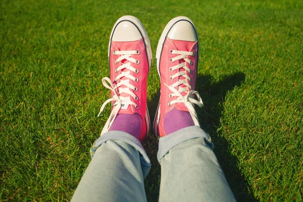 手结鞋带粉色运动鞋在自然界 男人的腿穿蓝色牛仔裤 薰衣草袜穿绿草 复制空间 室外开枪 — 图库照片
