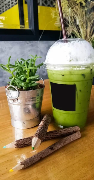 アイス緑茶 ミルク付きアイス抹茶ラテ紅茶 プラスチックカップにミルクをつけたアイス緑茶を白の背景に対して金属テーブルの上に — ストック写真