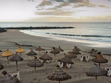 Sandy beach gün batımında güneş şemsiyesi ile. Tenerife Adası.