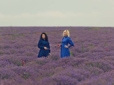 Mavi elbiseler lavanta alana poz iki kız.