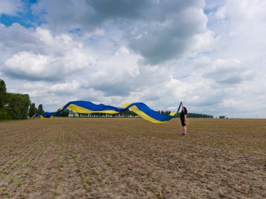 Alanda büyük bir Ukraynalı bayrağı ile genç inanılmaz güzel kız. Ukrayna Bağımsızlık günü.