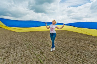 Alanda büyük bir Ukraynalı bayrağı ile genç inanılmaz güzel kız. Ukrayna Bağımsızlık günü.