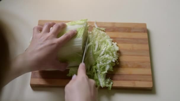 Une fille coupe du chou chinois avec un gros couteau . — Video