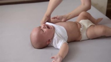 Anne ağlayan yeni doğmuş bir bebeği giydiriyor..