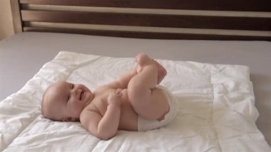 Sevimli bebek sırt ında yatıyor ve kollarını ve bacaklarını hareket ettiriyor.