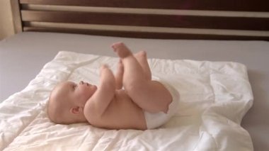 Sevimli bir bebek yatakta yuvarlanıyor.