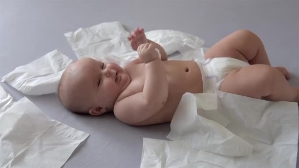 Bébé mignon est couché et jouer avec des serviettes blanches . — Video