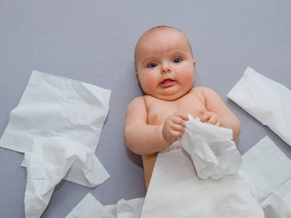 灰色の背景に幸せな赤ちゃんは 紙ナプキンで遊ぶ クローズ アップ — ストック写真