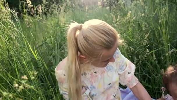 Küçük kızı olan genç bir kız çimlerin arasında oynuyor.. — Stok video