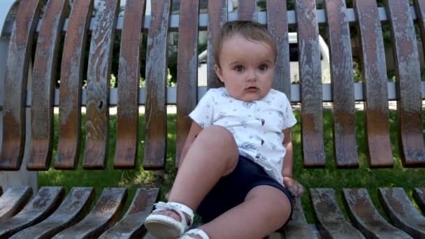 En arg liten flicka sitter på en parkbänk.. — Stockvideo