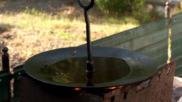 Кипящее масло в большой сковороде над открытым огнем. — стоковое видео