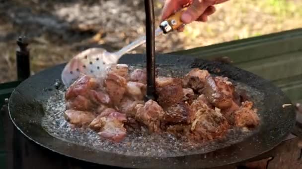 Vlees koken boven een vuur in een grote koekenpan. Sluitingsdatum. — Stockvideo