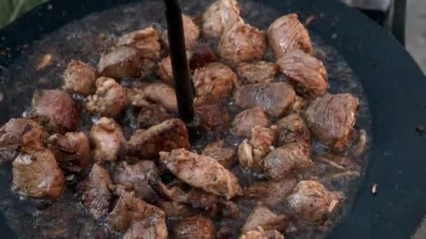 Vlees koken boven een vuur in een grote koekenpan. Bovenaanzicht. — Stockvideo