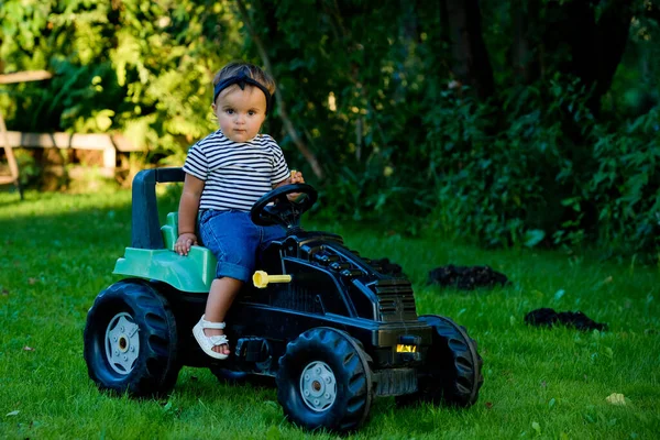 庭でおもちゃのトラクターで遊んでいる女の子 — ストック写真