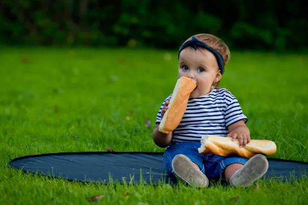 Una Niña Bonita Sienta Césped Jardín Sostiene Una Baguette Fresca — Foto de Stock