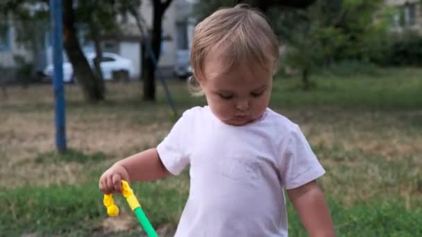 Porträtt av barn i orange stövlar drar en leksak och går genom pölen efter regnet. — Stockvideo