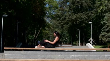 Genç esmer kadın bir bankta uzanıyor. Yavaş çekim.