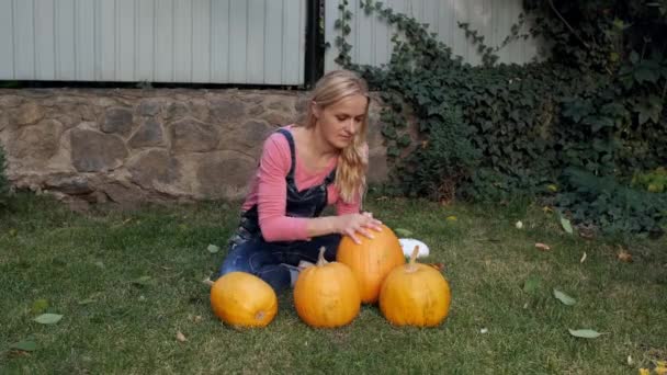 Jeune femme choisit citrouille pour Halloween sur la pelouse. — Video