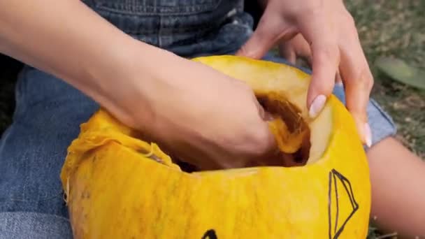 Les mains des femmes et des bébés sculptent une effrayante citrouille d'Halloween. — Video