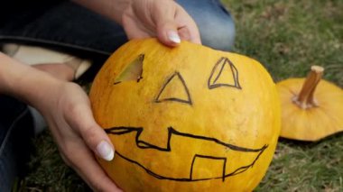 Dişi eller korkunç bir cadılar bayramı kabağı oyar. Ağır çekim. Cadılar Bayramı partisi için Jack Lantern. Yakın plan..