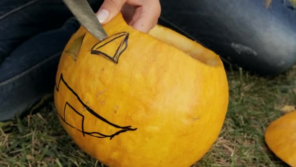 Les mains féminines sculptent une effrayante citrouille d'Halloween. Lanterne Jack pour la fête d'Halloween. Gros plan. — Video