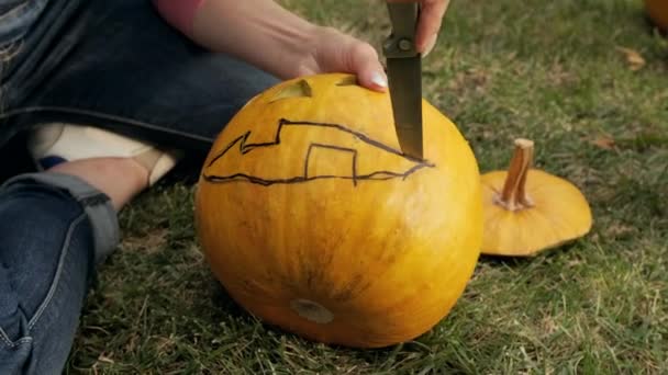 Les mains féminines sculptent une effrayante citrouille d'Halloween. Lanterne Jack pour la fête d'Halloween. Gros plan. — Video