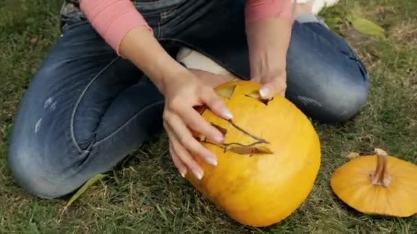 As mãos femininas entalham uma abóbora assustadora do Dia das Bruxas. Lanterna Jack para a festa de Halloween. Close-up. — Vídeo de Stock