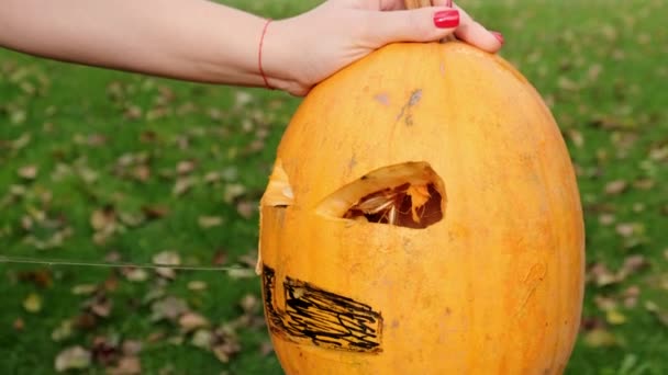 Las manos femeninas tallan una calabaza de halloween aterradora. Primer plano. Movimiento lento. — Vídeos de Stock