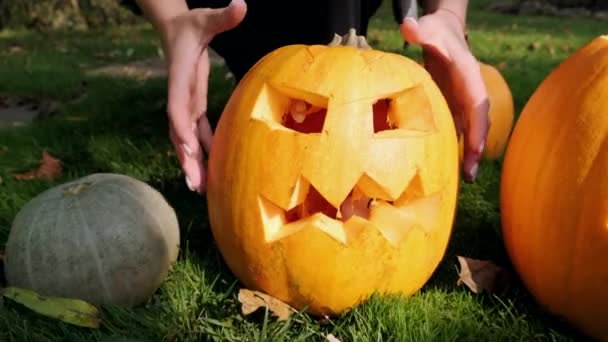 As mãos femininas tocam uma abóbora de Halloween assustadora. Close-up. Movimento lento. — Vídeo de Stock