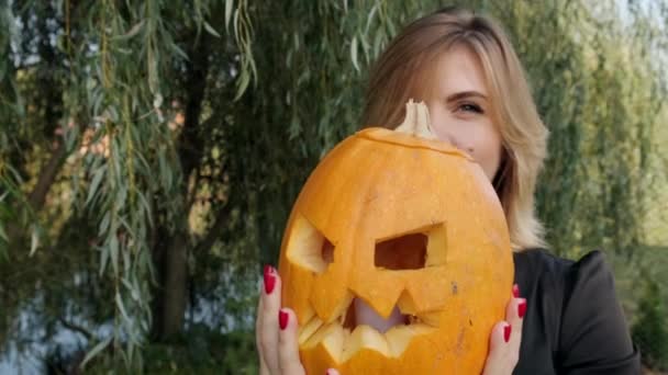 Mladá žena drží v rukou strašidelnou halloweenskou dýni. Detailní záběr. Zpomalený pohyb. — Stock video