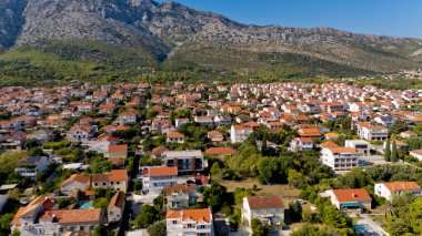 Sahili ve arka planında dağ olan küçük bir kasaba. Evler çoğunlukla beyaz ve kırmızıdır.