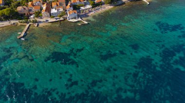 Arka planda bir kasaba olan mavi bir okyanus. Su dalgalı ve kasaba küçük.