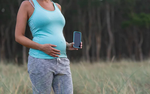 Akıllı Telefon Açık Tutan Hamile Sportif Kadın Bekleyen Anne Karnına — Stok fotoğraf