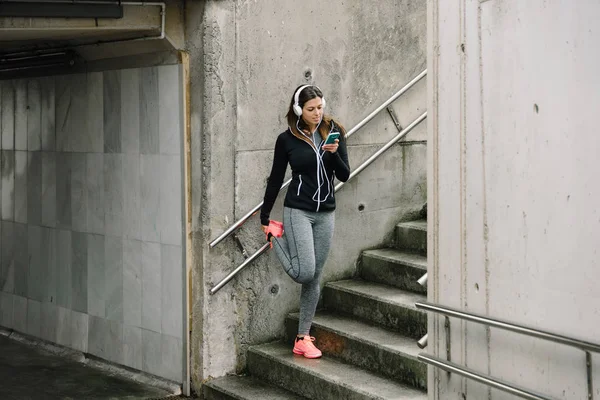Sportowy Kobieta Słuchawkami Rozciąganie Nogi Rozgrzewkę Przed Uruchomieniem Mieście Lekkoatletka — Zdjęcie stockowe