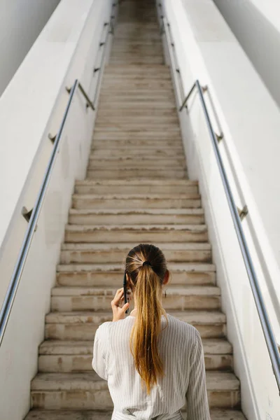 ビジネスやプロの成功の概念 都市長い階段に向かって携帯電話で女性の背面図 — ストック写真